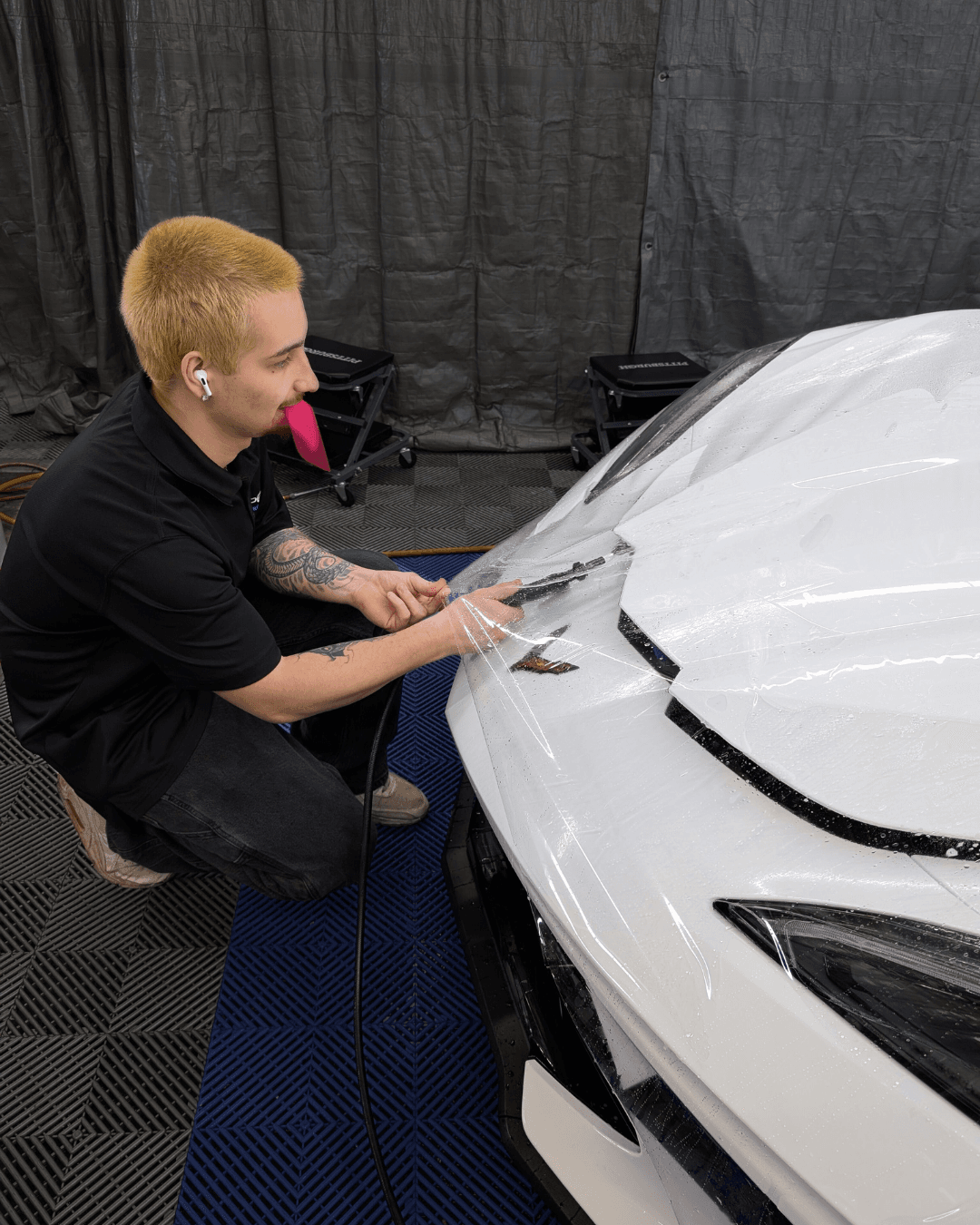Paint Protection Film Installation on Corvette at Loupe Detailing Technician installing paint protection film on white Corvette at Loupe Detailing in Amherst, NY