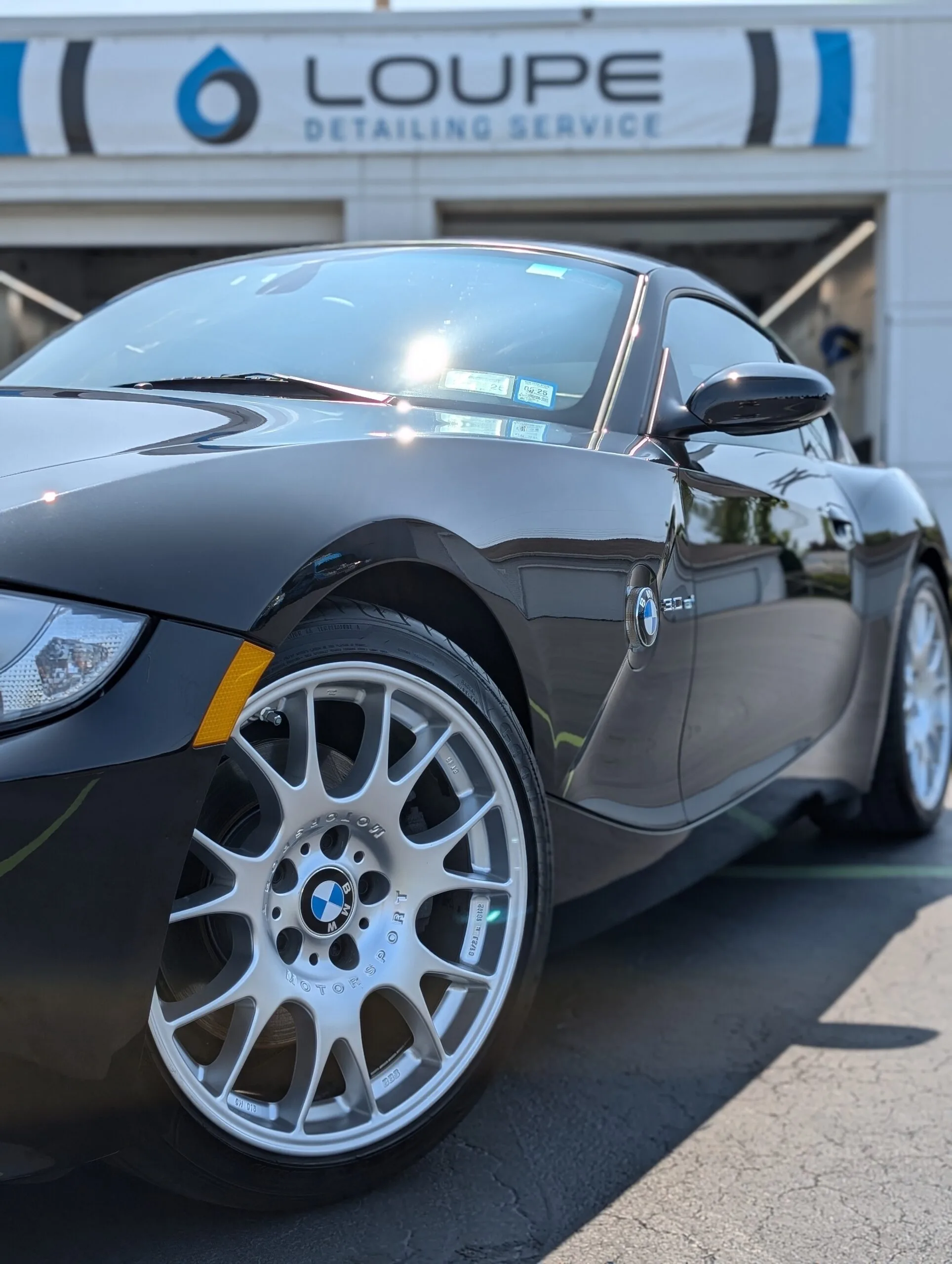 BMW Z4 After Ceramic Coating at Loupe Detailing Amherst Black BMW Z4 polished and ceramic coated at Loupe Detailing in Amherst, NY with shop signage in background