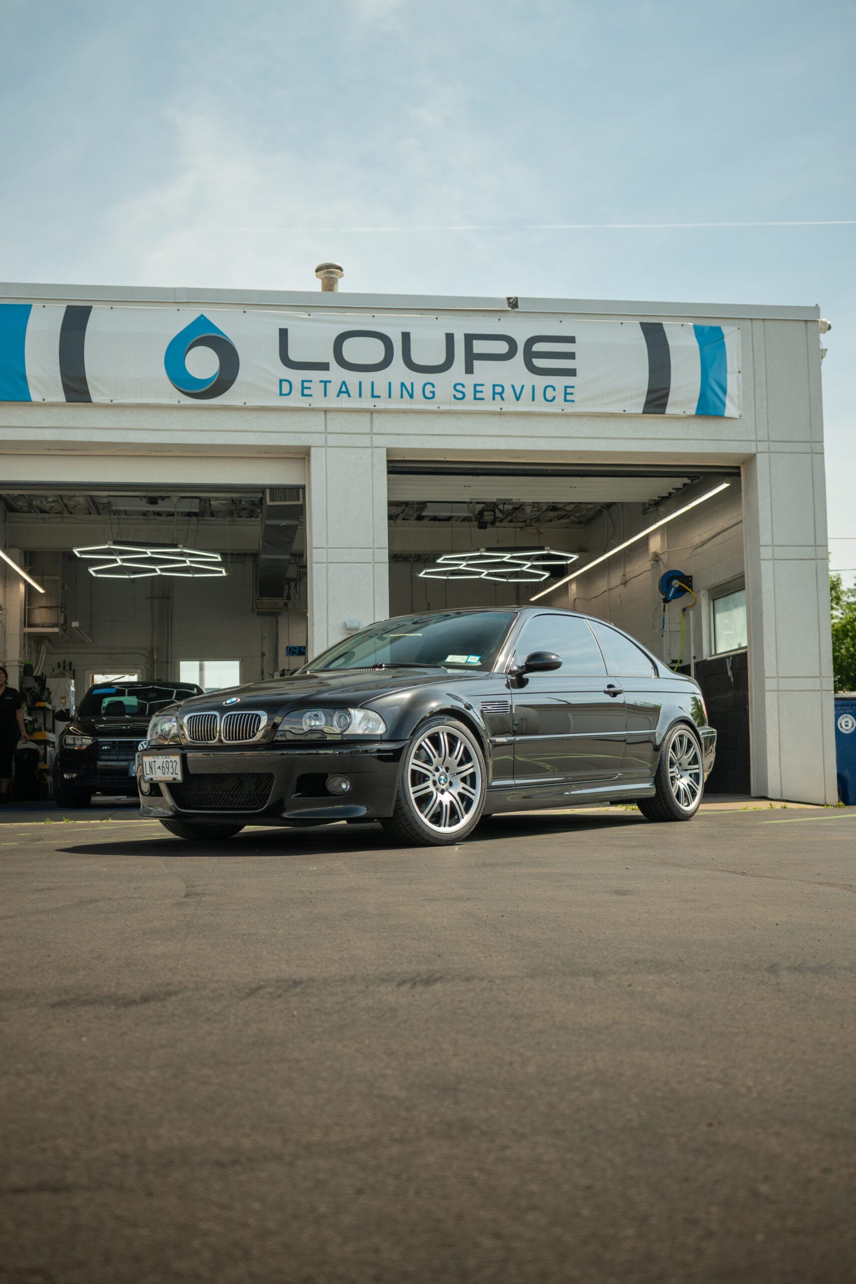 Black BMW with ceramic window tint parked outside Loupe Detailing Service in Amherst, NY